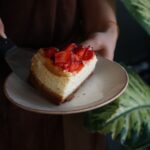 Kawałek sernika z truskawkami na ceramicznym talerzu
